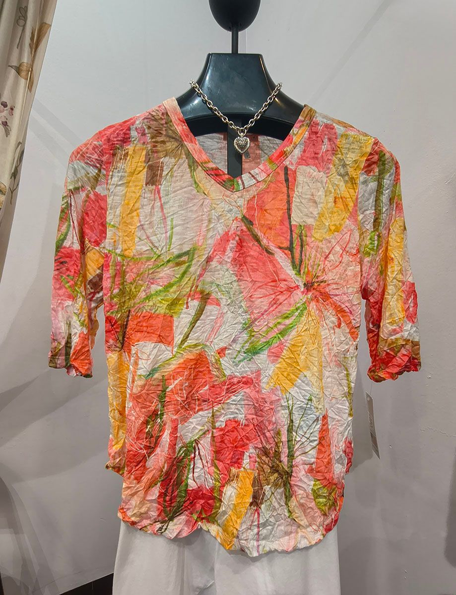 Abstract multicolor short-sleeve blouse on a mannequin, with red, yellow, and green brushstroke patterns.