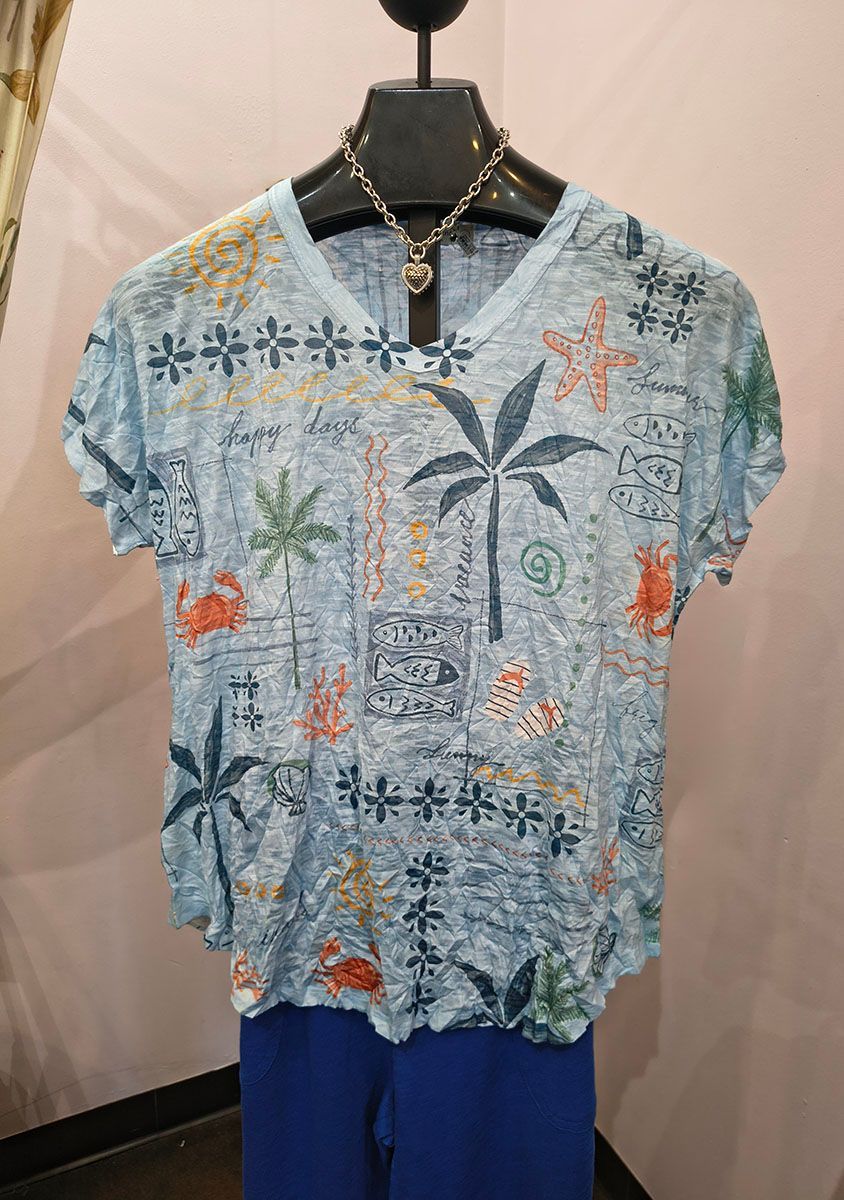 Blue patterned short-sleeve shirt on a mannequin, with orange and dark floral designs and blue pants below.