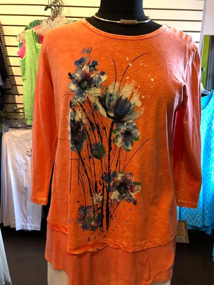 Orange floral long-sleeve tunic dress on a mannequin in a clothing store