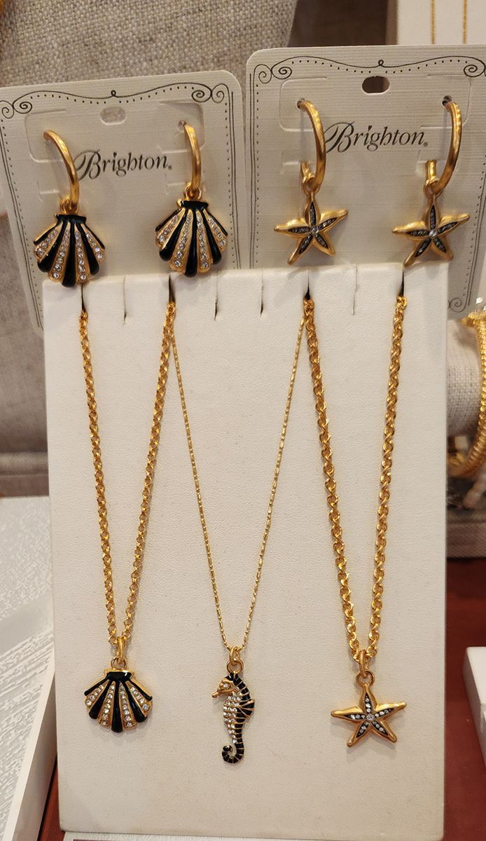Gold and black shell and star jewelry set displayed on white cards against a beige background