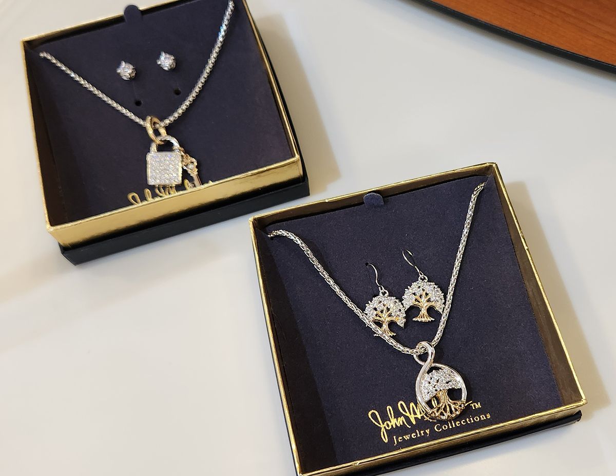 Two gold jewelry sets in black gift boxes on a light surface.