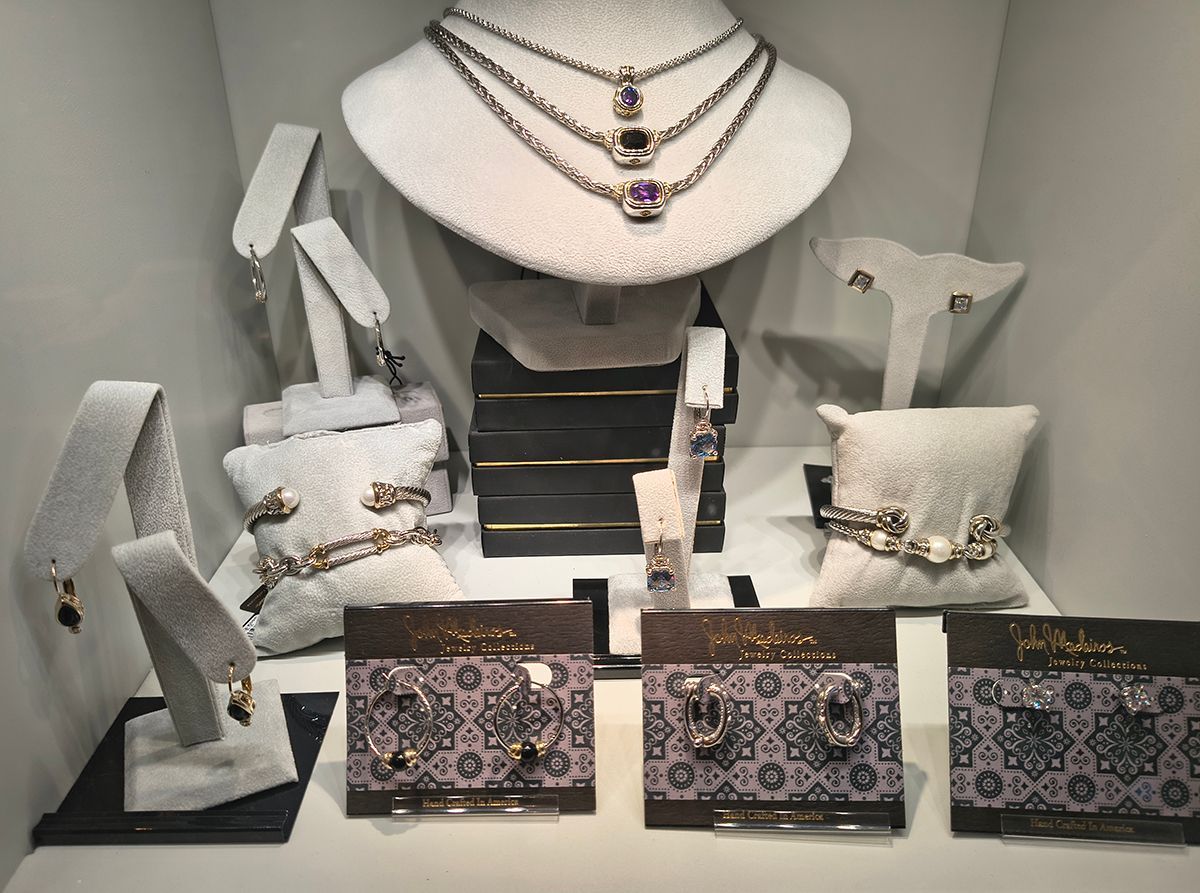 Jewelry display with layered necklaces, bracelets, rings, and patterned wallet cases on stands