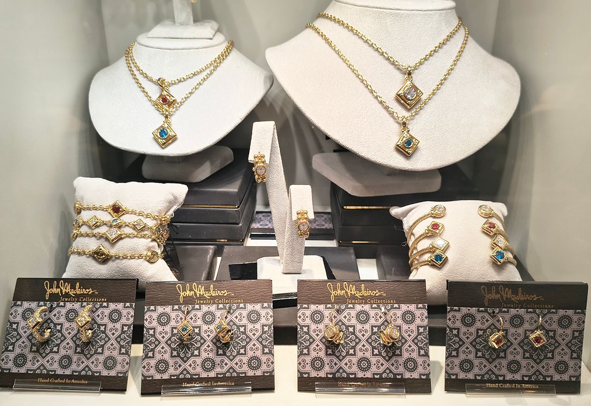 Jewelry display with gold necklaces, bracelets, and floral-patterned boxes on black stands