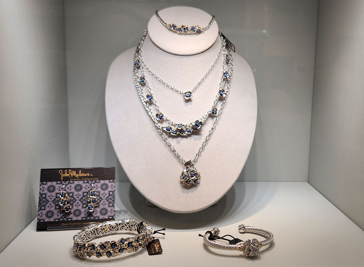 Jewelry store display with diamond necklace set, bracelet, ring, and matching earrings on white bust and tray