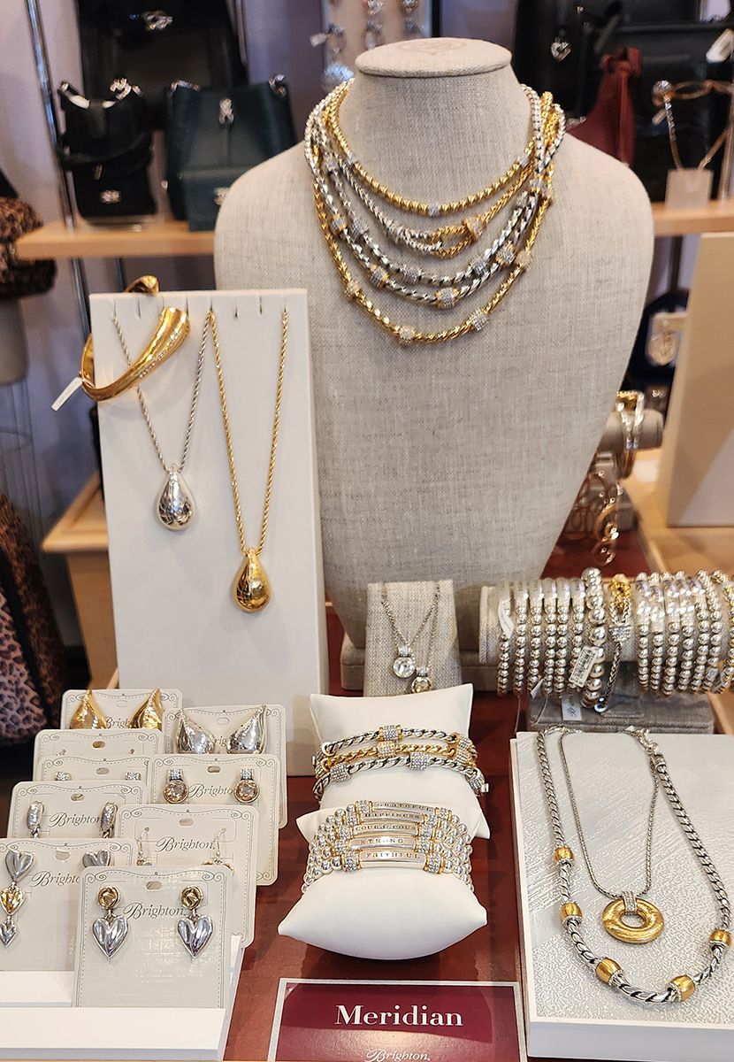Jewelry display with gold and silver necklaces, bracelets, and rings on a mannequin and stands