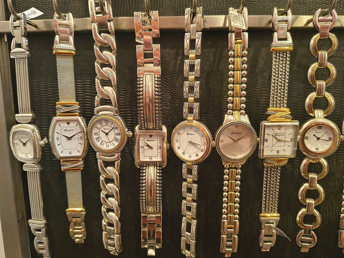 Assorted gold and silver wristwatches displayed in a row on a dark background