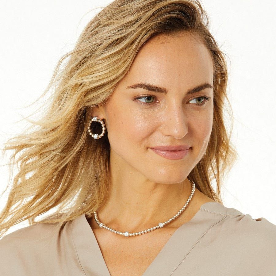 Portrait of a blonde woman wearing a beige top and pearl necklace, looking to the side with a slight smile.