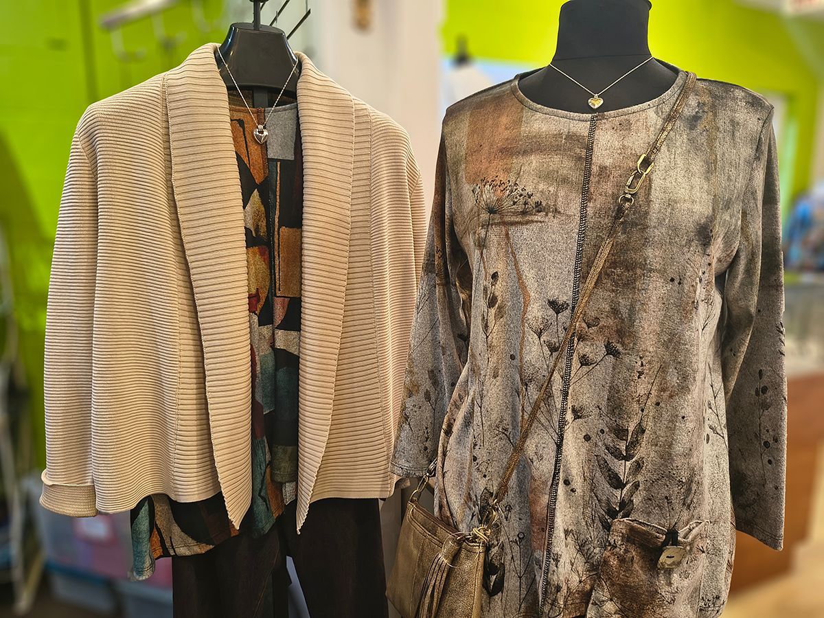Two patterned jackets displayed on mannequins, one beige and one brown, in a clothing shop.