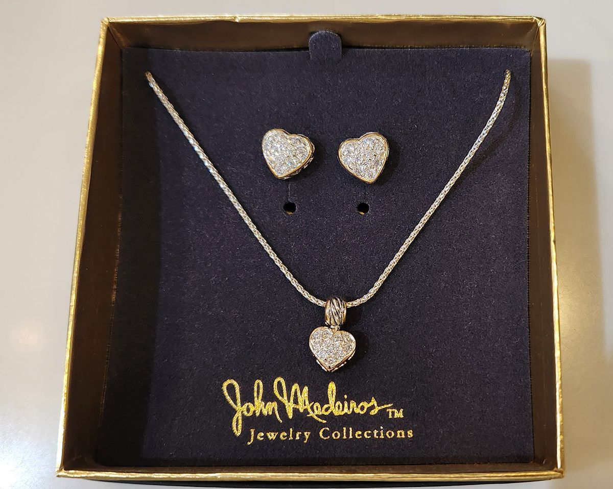 Heart-shaped jewelry set in a gold box with necklace and earrings on black velvet.