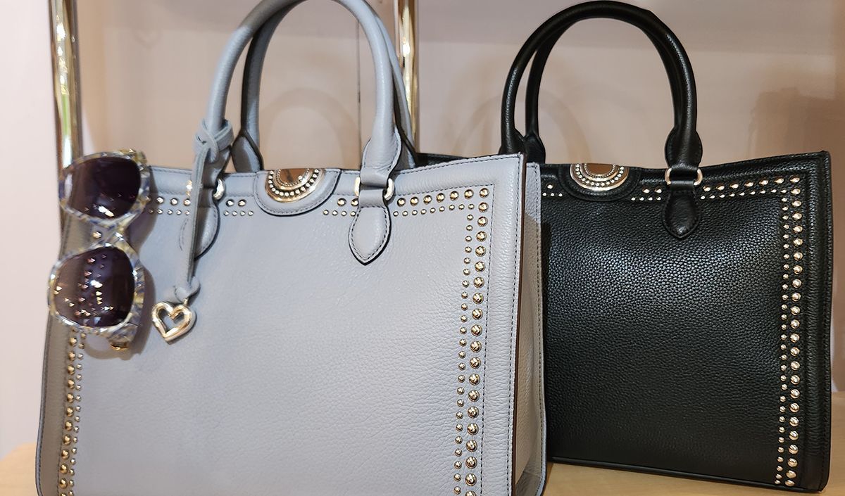 Two handbags, one gray and one black, with sunglasses in front on a light background
