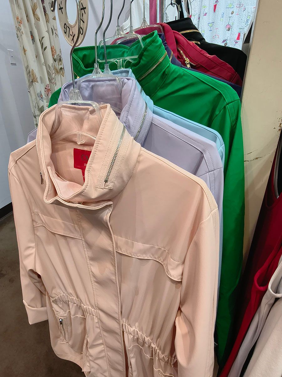 Rack of hanging jackets in beige, gray, green, and red at a clothing store