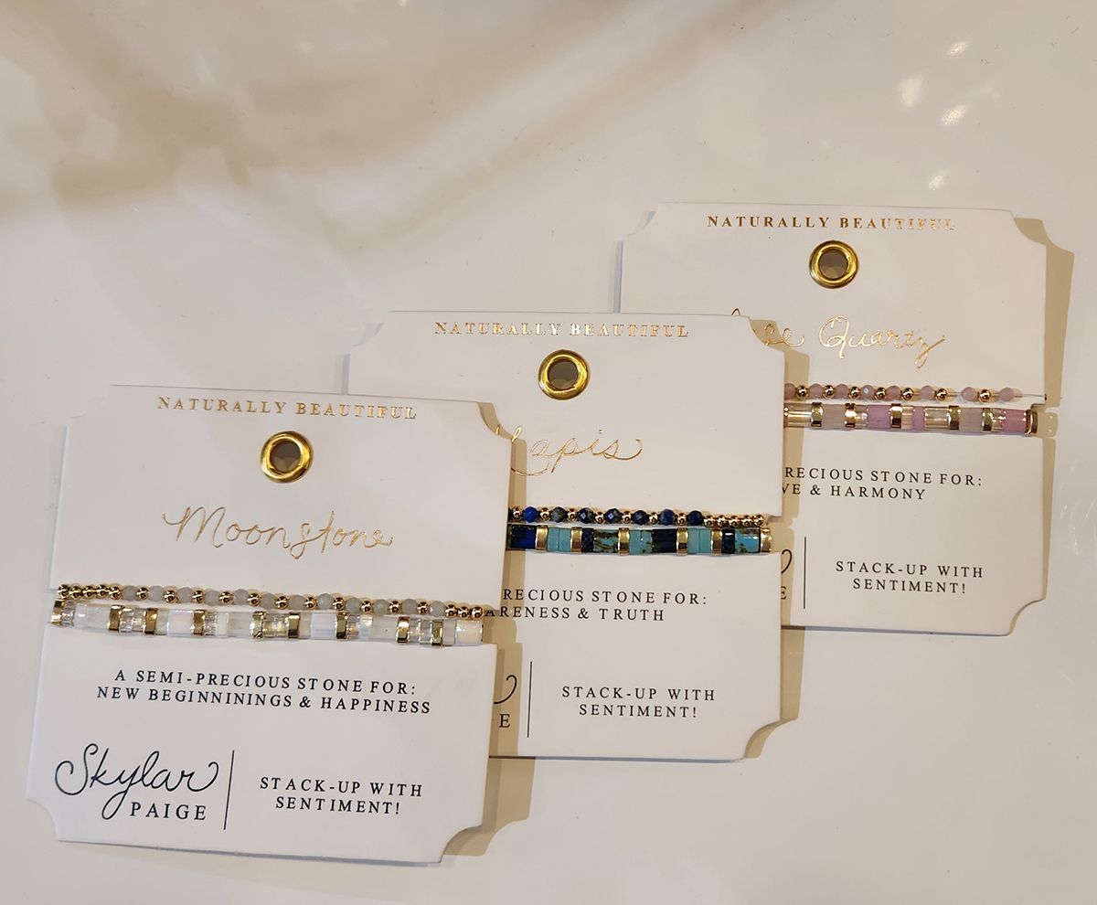 Three elegant white and gold branded cards with decorative script, arranged in a row on a light surface.