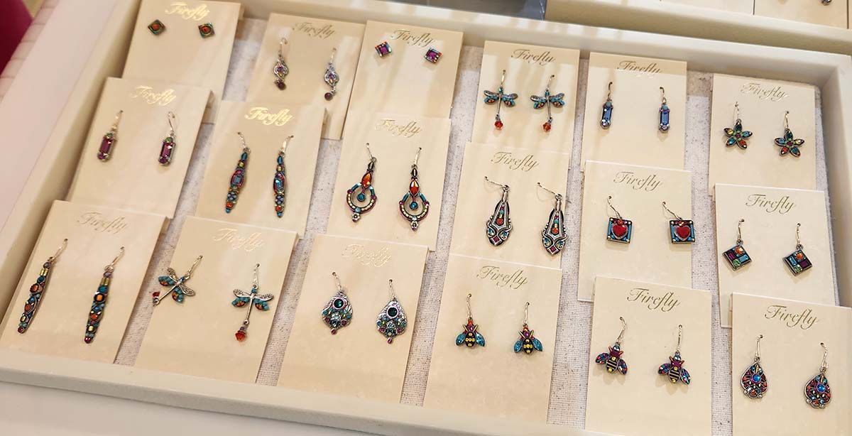 Tray of assorted dangling earrings and stud earrings displayed on white cards.
