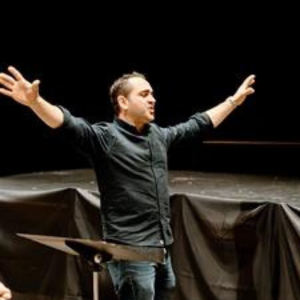 A man is standing on a stage with his arms outstretched.