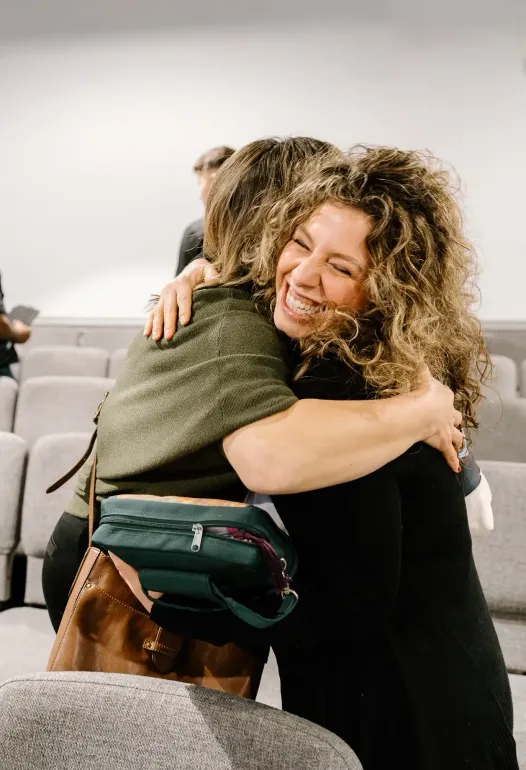 Two women are hugging each other in a room.