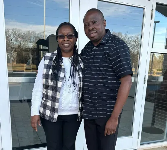 A man and a woman are posing for a picture in front of a building.