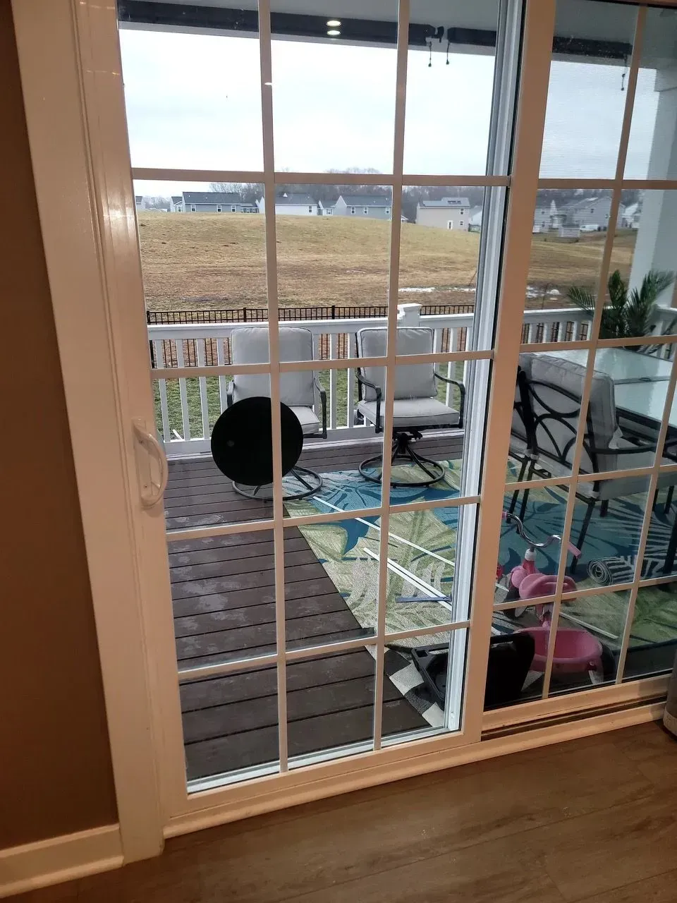 A sliding glass door leading to a deck with chairs and a table.