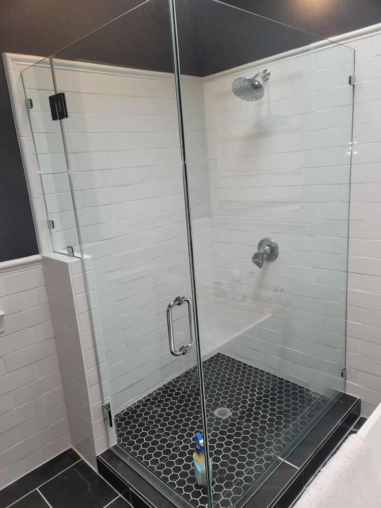 A bathroom with a walk in shower with a glass door.
