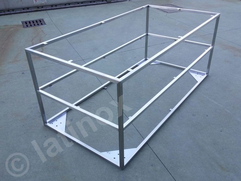 Telaio rettangolare in metallo su una superficie in cemento. Presenta una base inferiore e due strati di supporto.