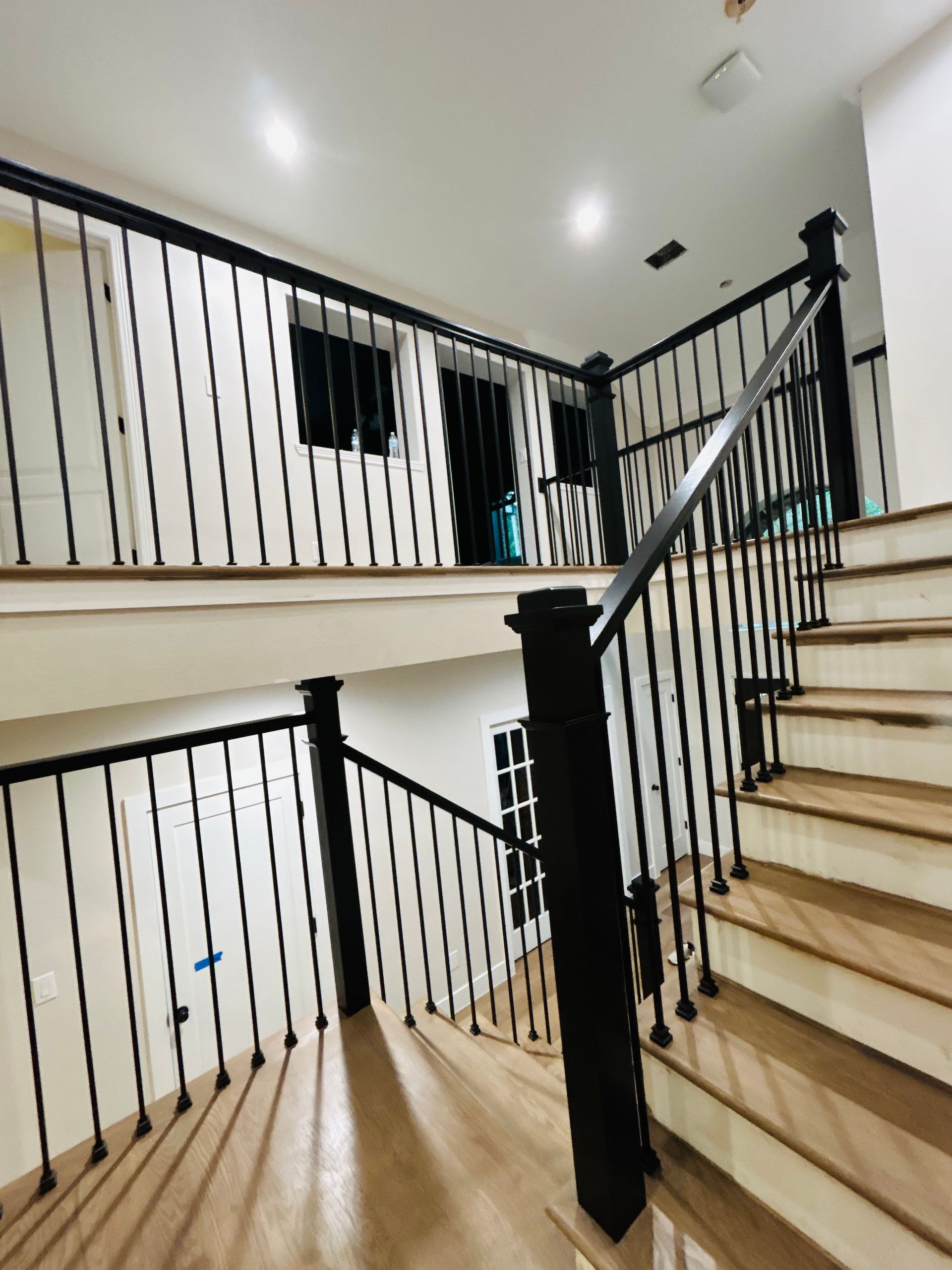 Stairwell with beige steps, black railings, and white walls in a modern interior.