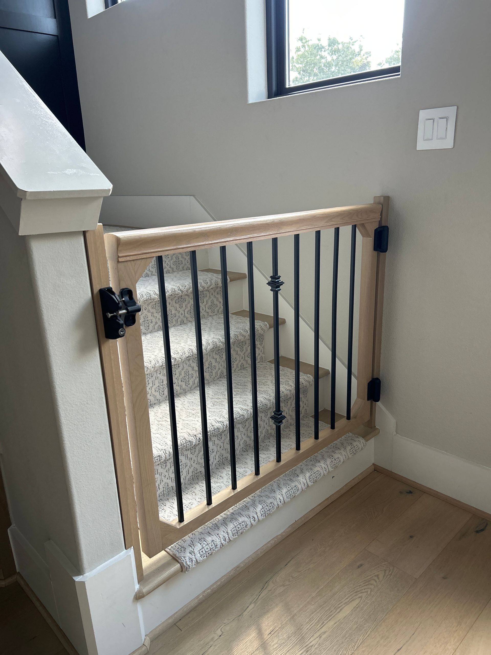 Wood-framed black metal gate blocking a stairway landing inside a home