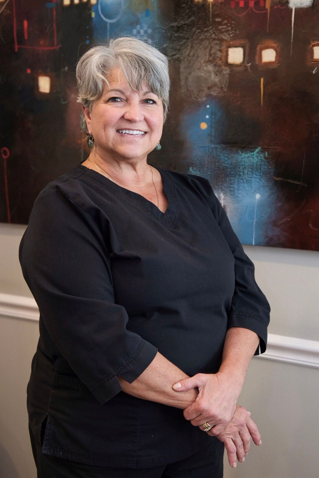 A woman in a black scrub top is smiling for the camera.