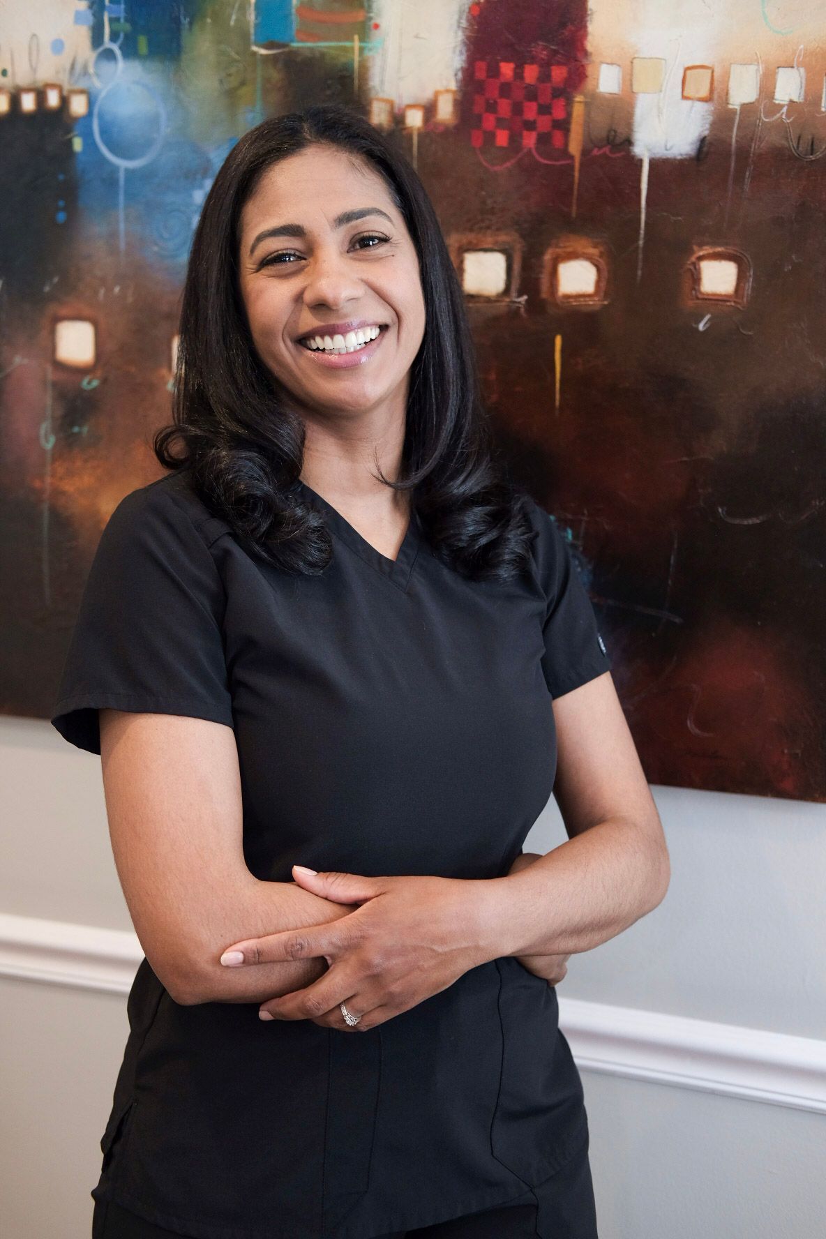 A woman in a black scrub top is smiling for the camera.