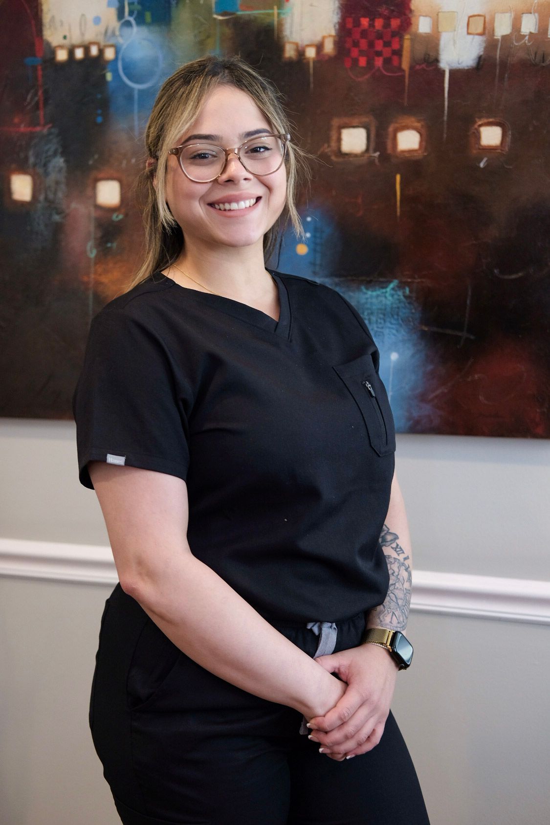 A woman in a black scrub top is smiling for the camera.