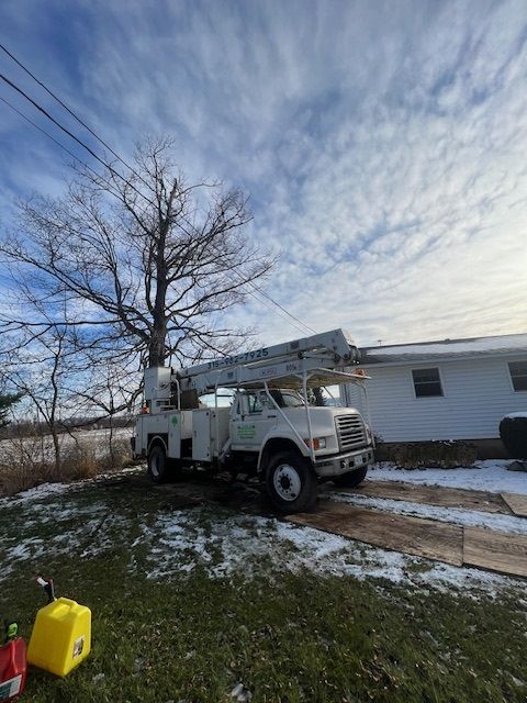 A white truck with a crane on top of it is parked in front of a house.