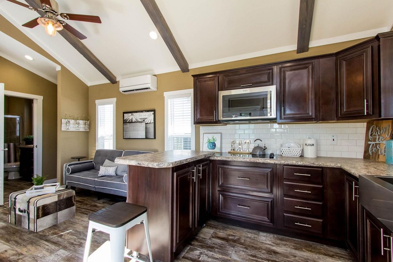 Open-concept living room and kitchen with dark wood cabinets, gray sofa, and high ceilings