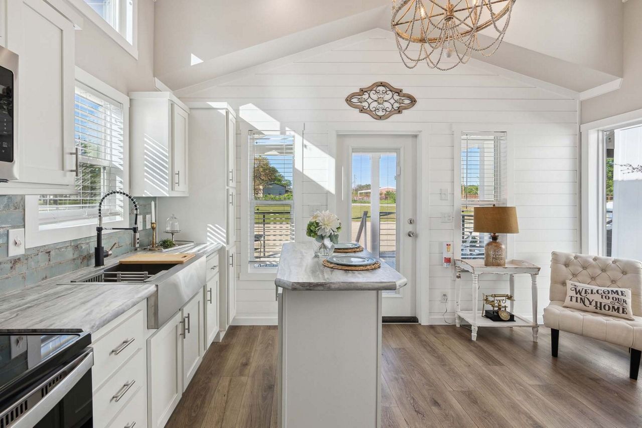 Bright white kitchen and dining area with island, wood floors, and large windows