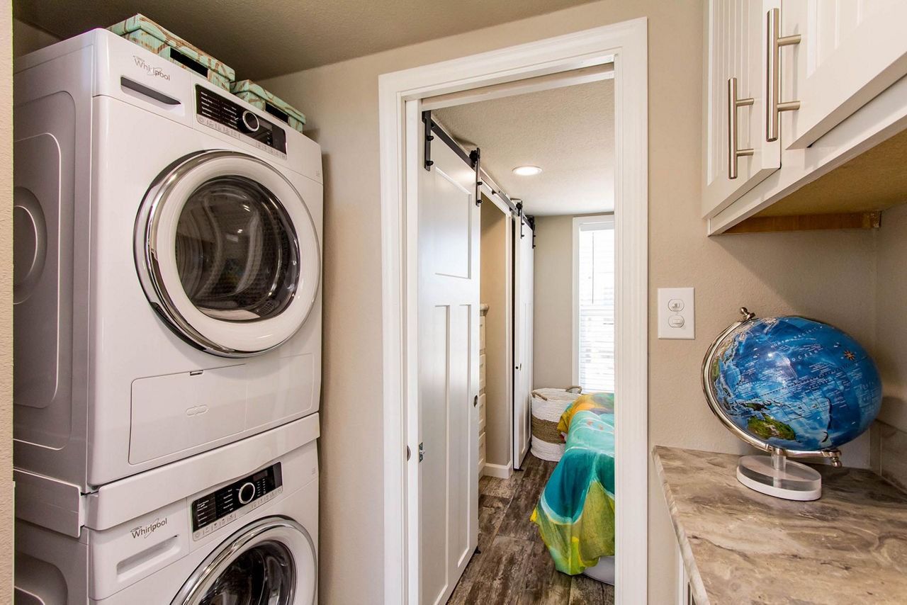 Laundry room with stacked washer and dryer, countertop, and blue globe on shelf