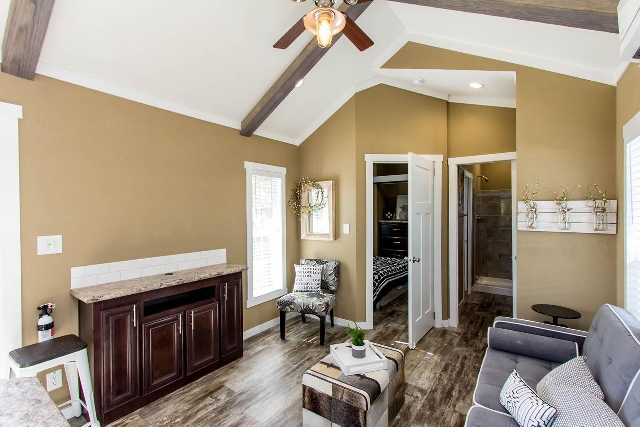 Living room with vaulted ceiling, dark wood cabinet, gray sofa, and open closet doors