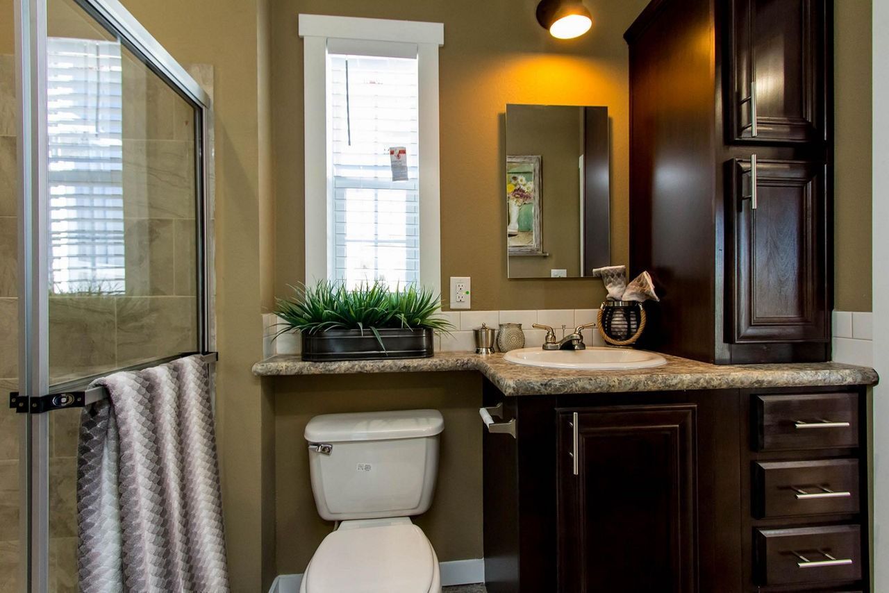 Small bathroom with vanity, sink, toilet, mirror, and window in warm lighting