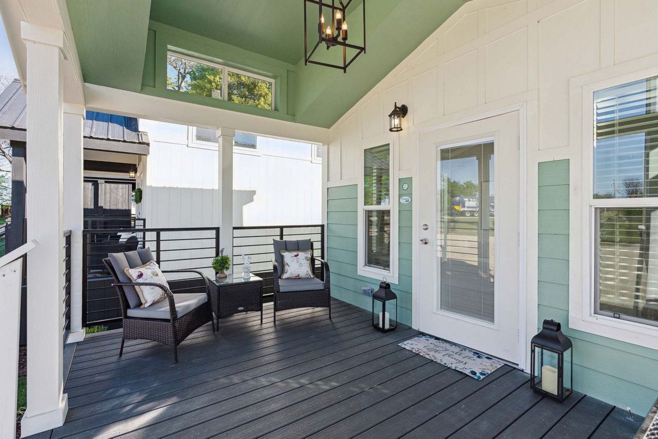 Covered porch with white chairs, dark floor, mint walls, and French doors under a green ceiling