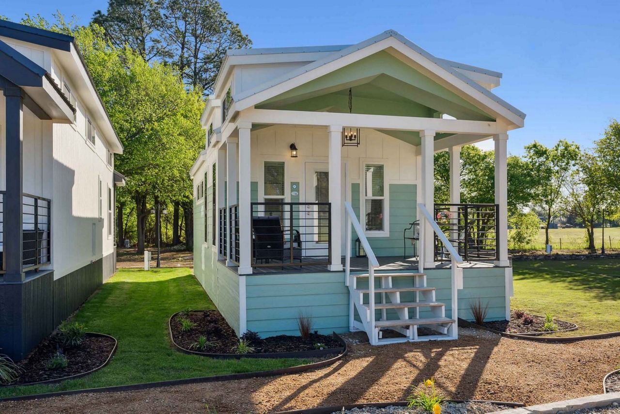 Small white and mint house with front porch and steps under a sunny blue sky