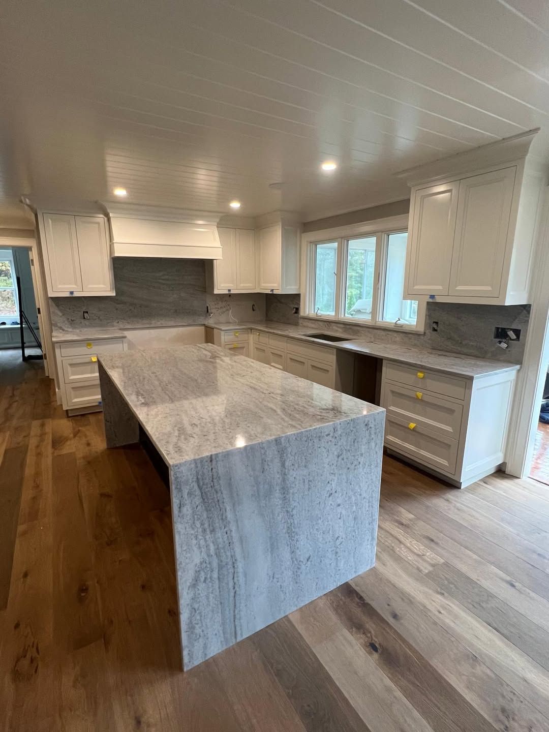 Client countertop installation with a waterfall island edge, matching backsplash and white cabinets