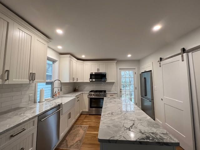 Client kitchen with white cabinets and a long gray-and-white veined countertop island