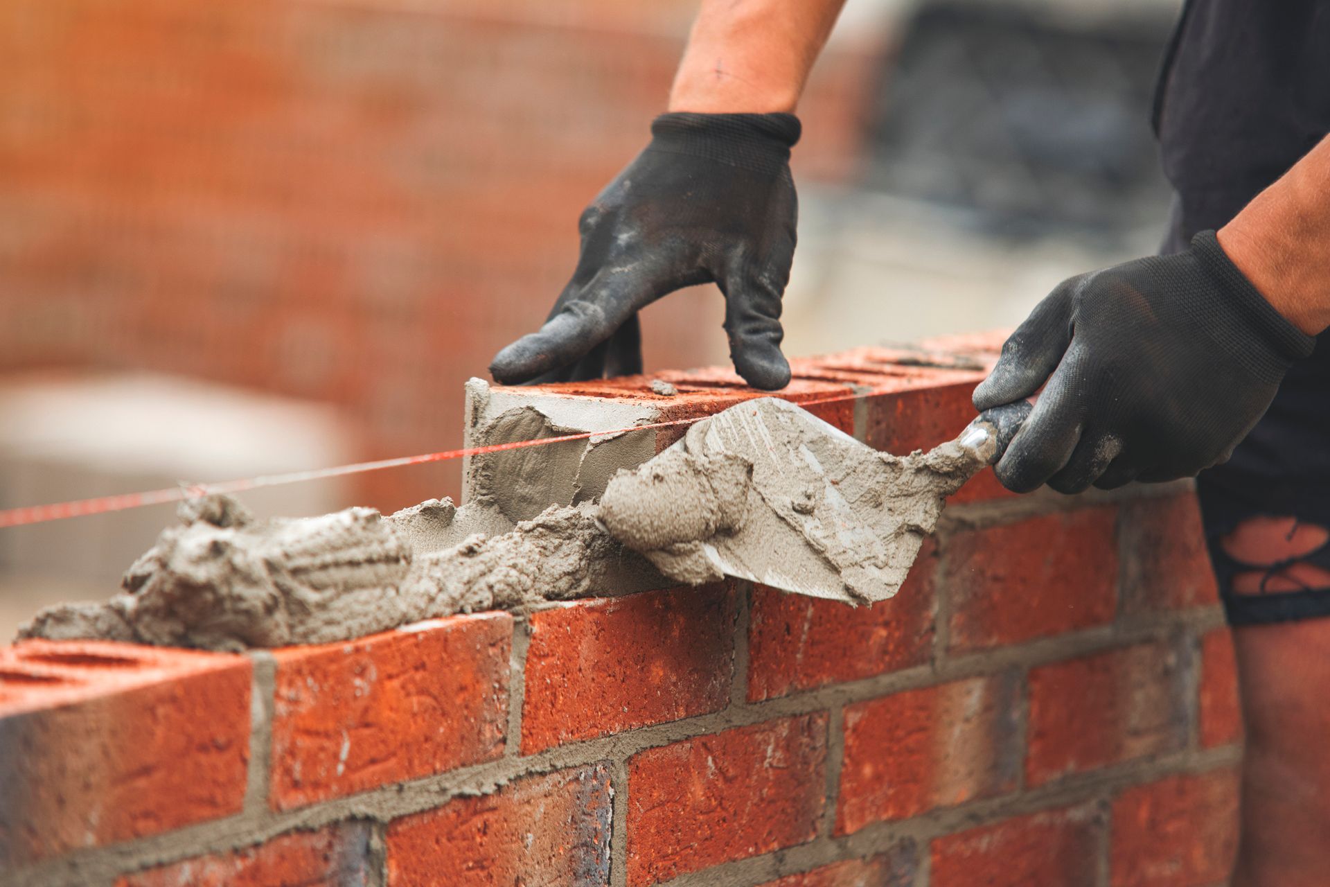 A man is laying bricks on a wall with a trowel
