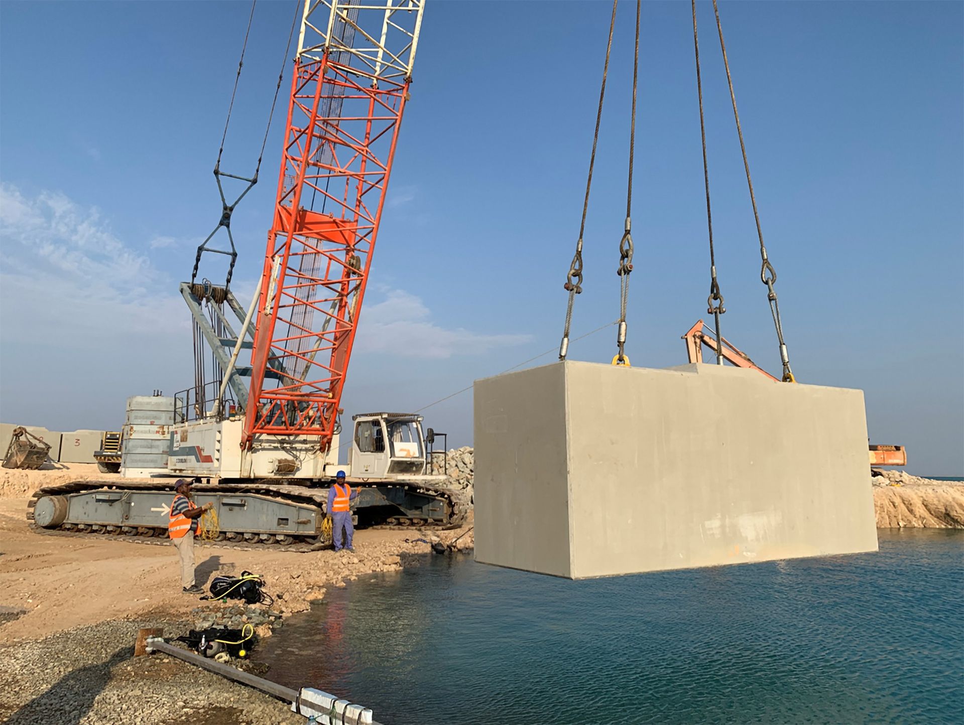 a large crane is lifting a large concrete block into the water
