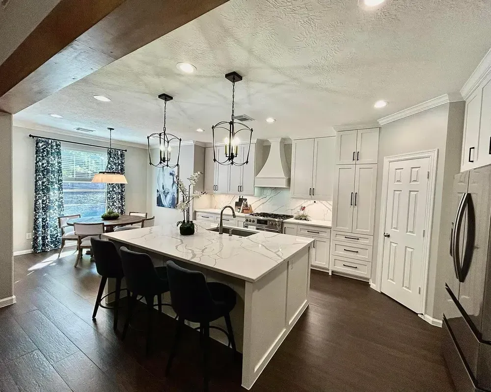 A kitchen with white cabinets and a large island in the middle.