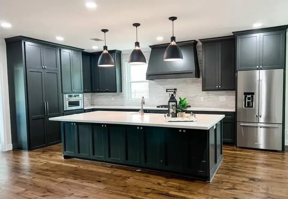 A kitchen with black cabinets , stainless steel appliances , and a large island.