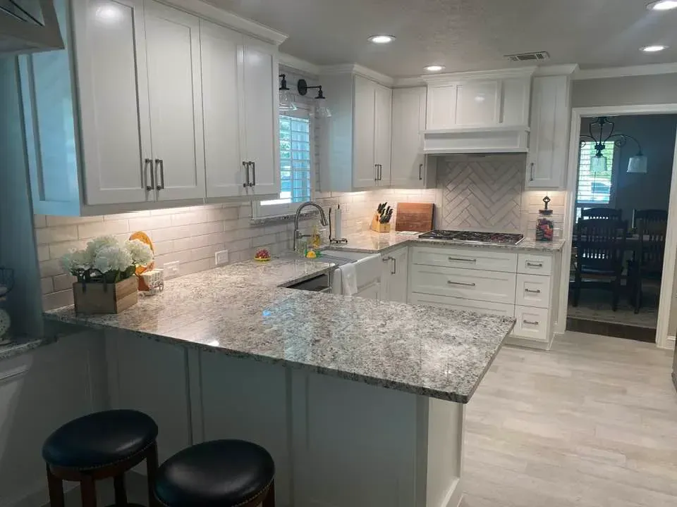 A kitchen with white cabinets and granite counter tops.