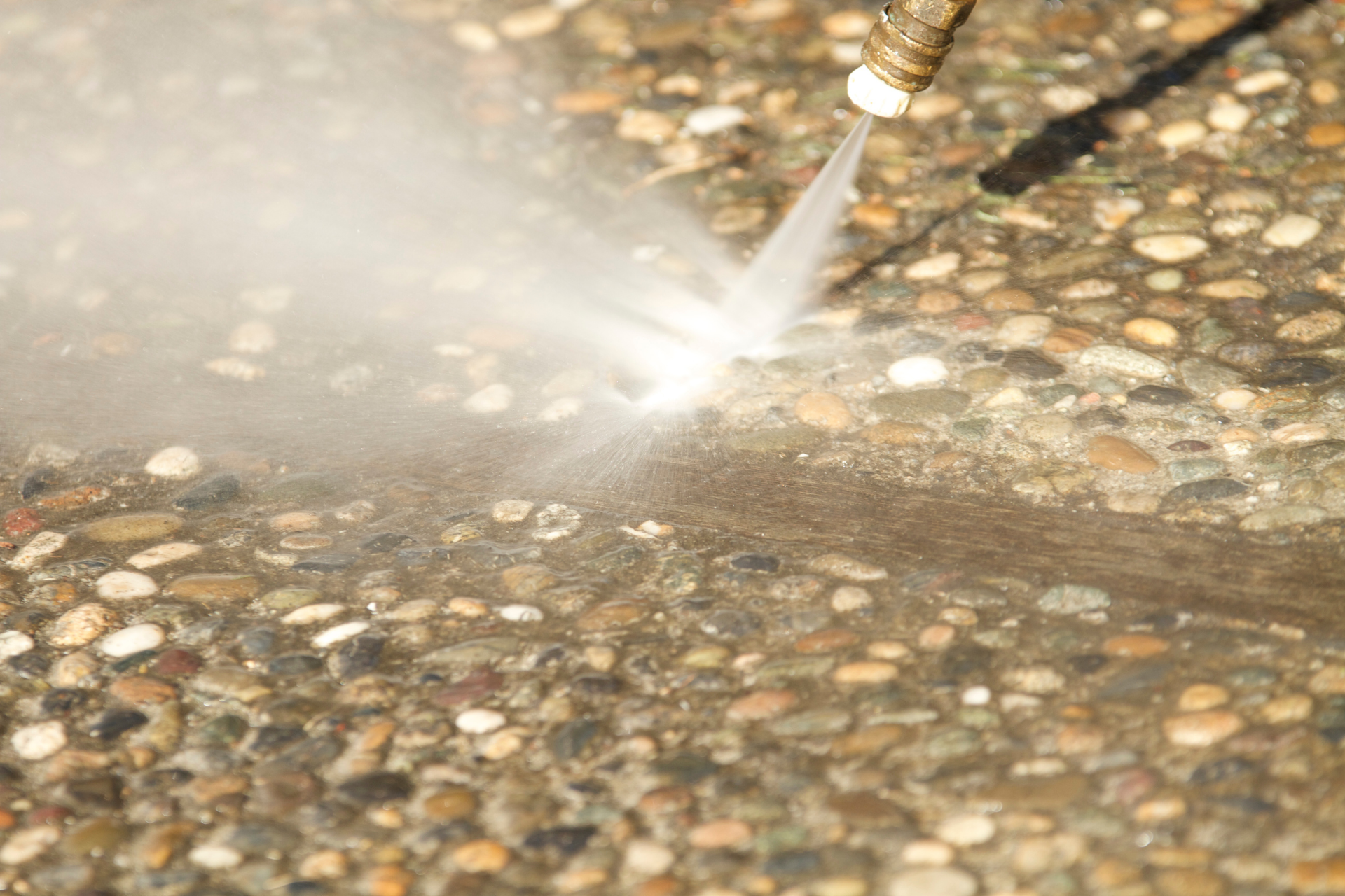 Pressure washer spraying water on a wet pebble surface