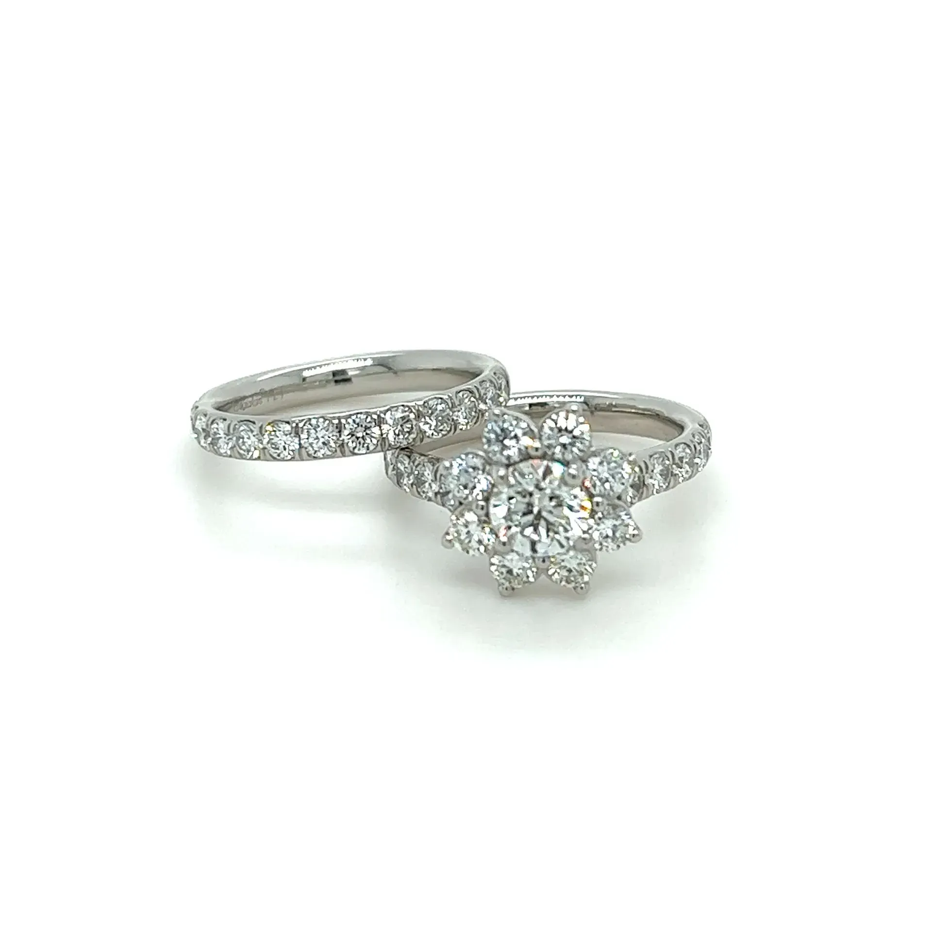 A wedding ring and engagement ring are on a white surface.