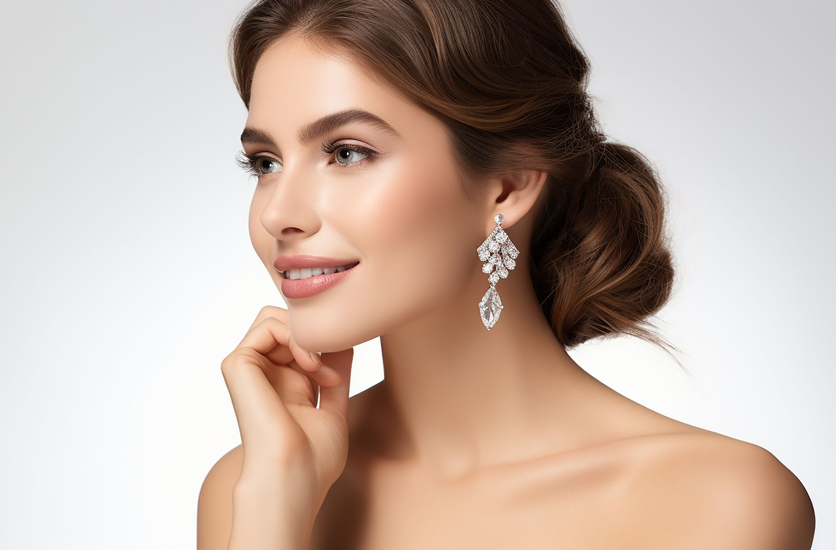 Elegant woman with pearl earrings, hair in an updo, posing against a light background.