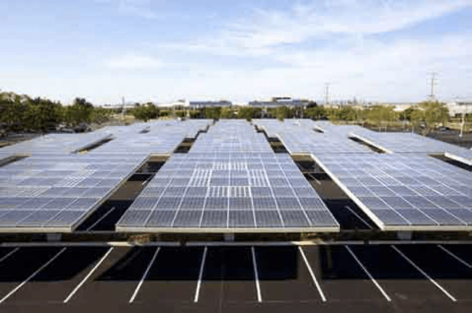 a lot of solar panels are sitting on top of a parking lot .