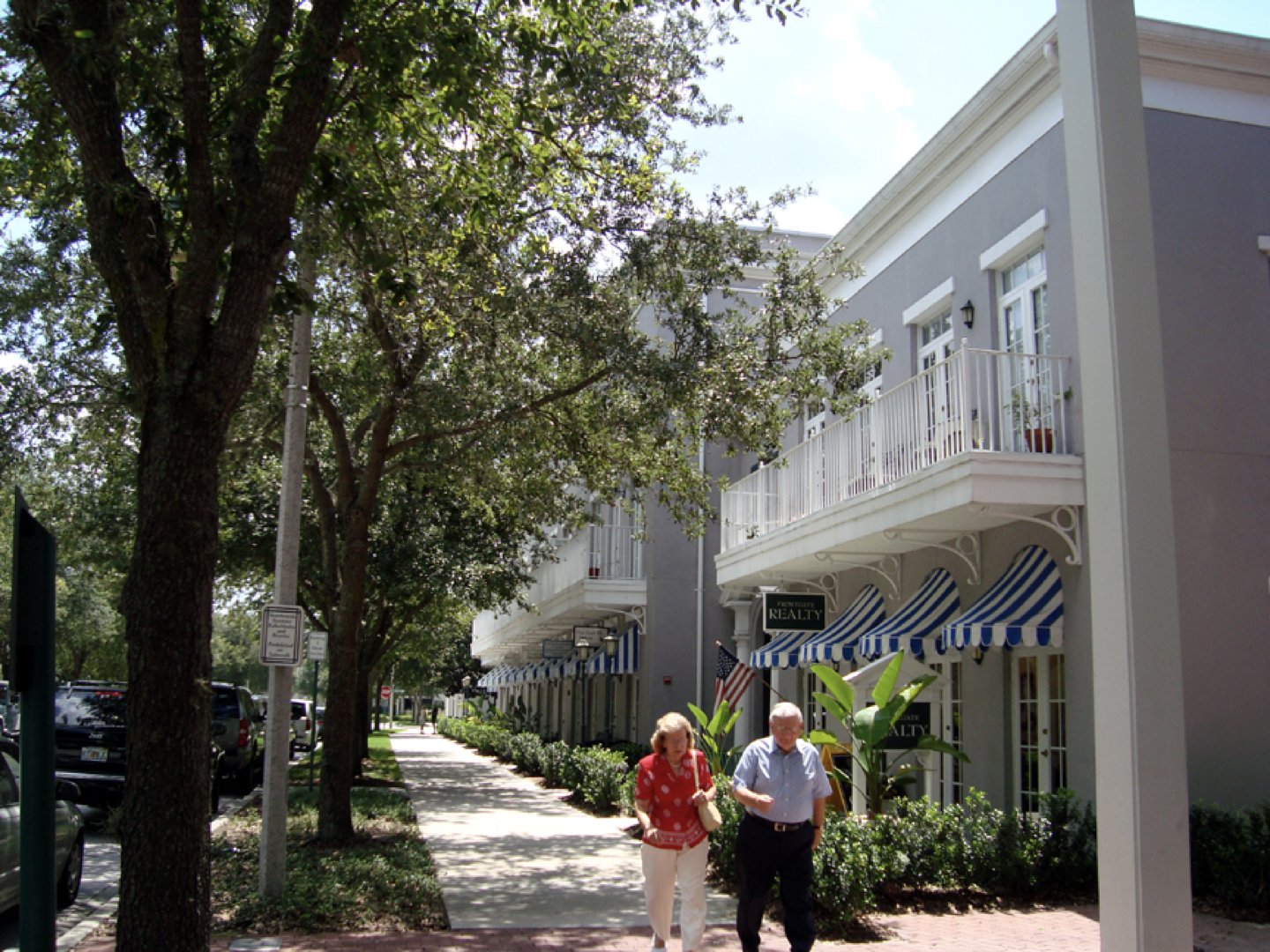 a couple walking down a sidewalk in front of a building