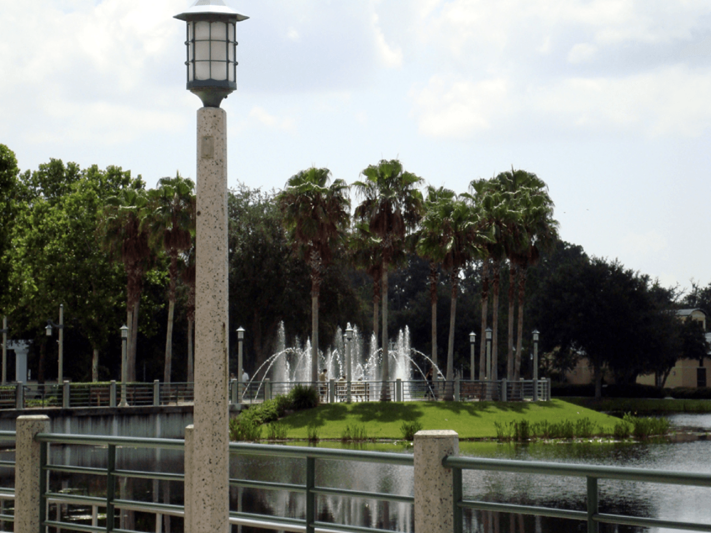 a fountain in a park with palm trees in the background