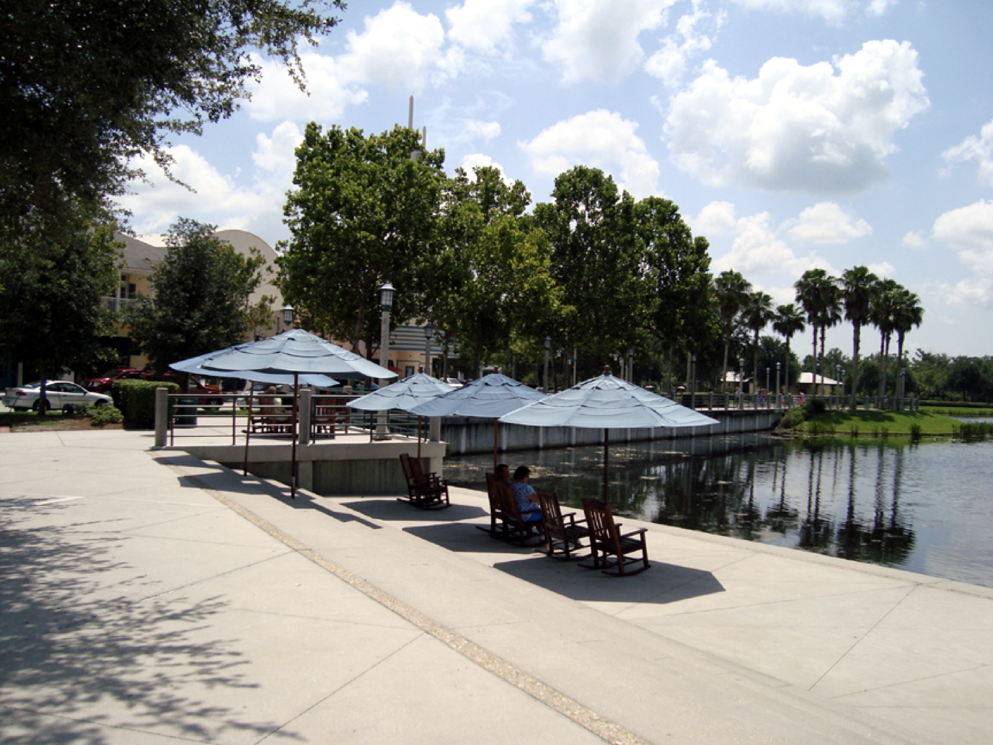 a couple sits under umbrellas near a lake